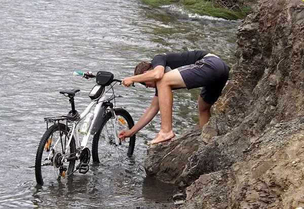 mencuci sepeda di tepi sungai